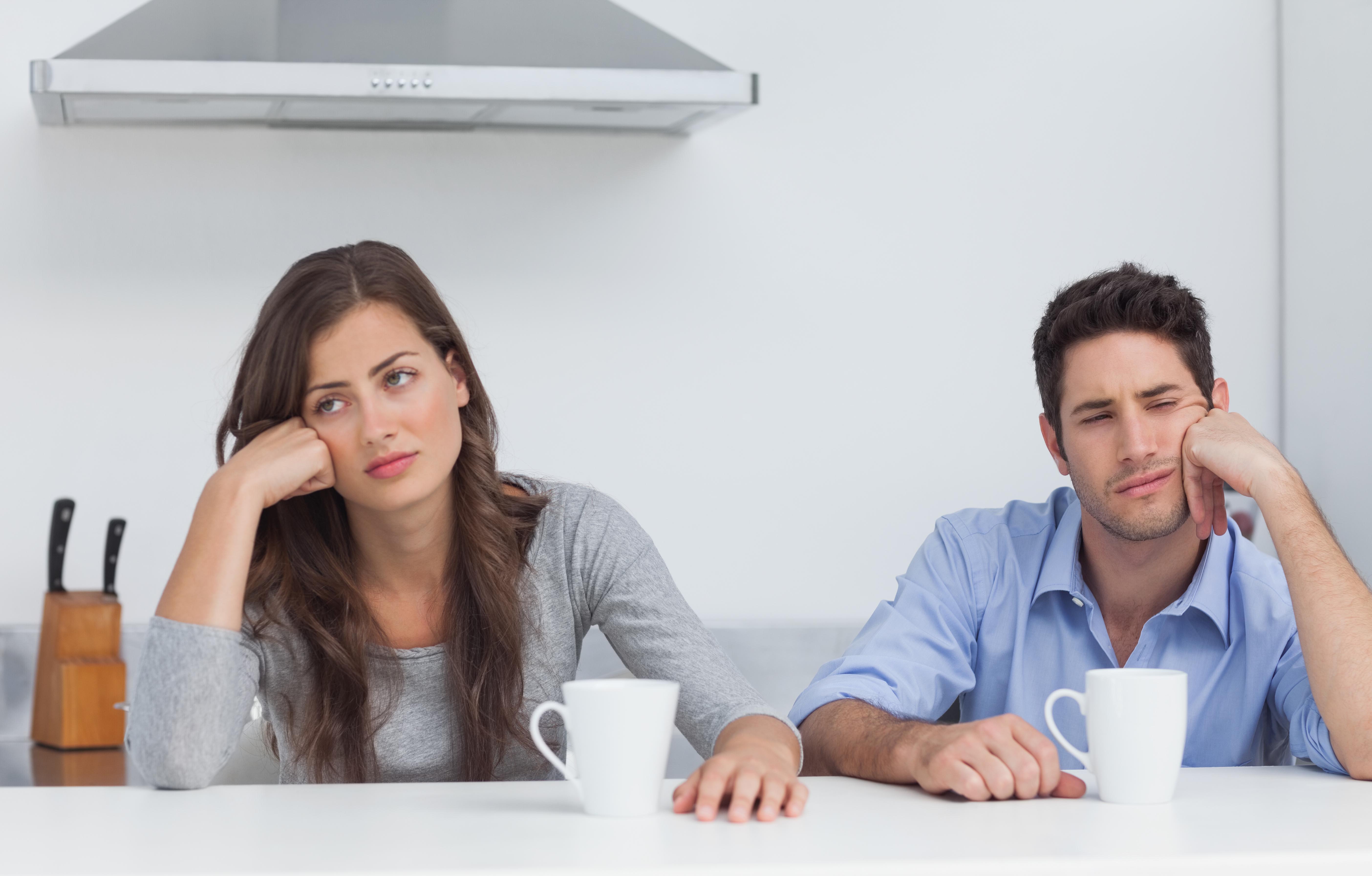 Tired couple sitting at the table with a cup of coffee in the kitchen